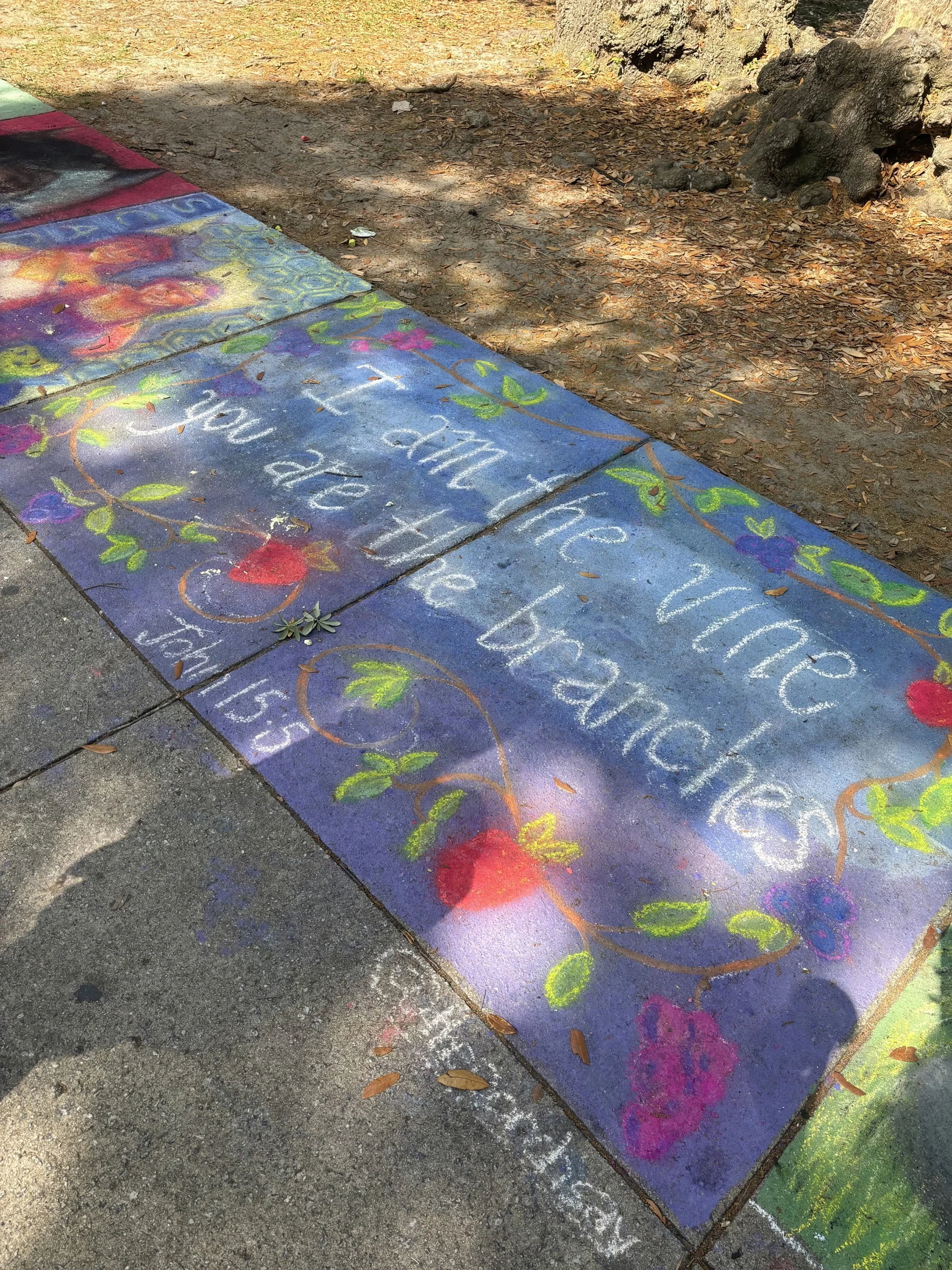 Sidewalk chalk mural lettered &ldquo;I am the vine, you are the branches&rdquo;.